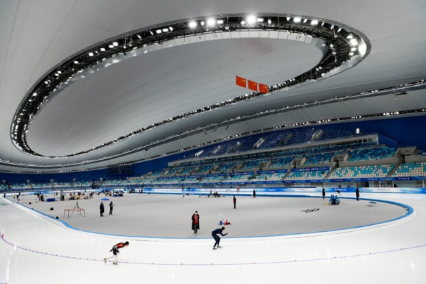Speed skating athletes training on the ice inside a large indoor arena