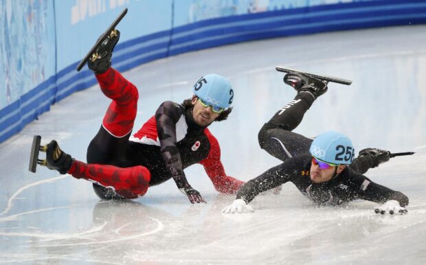 Two speed skating athletes falling on the ice during a race in a skating competition