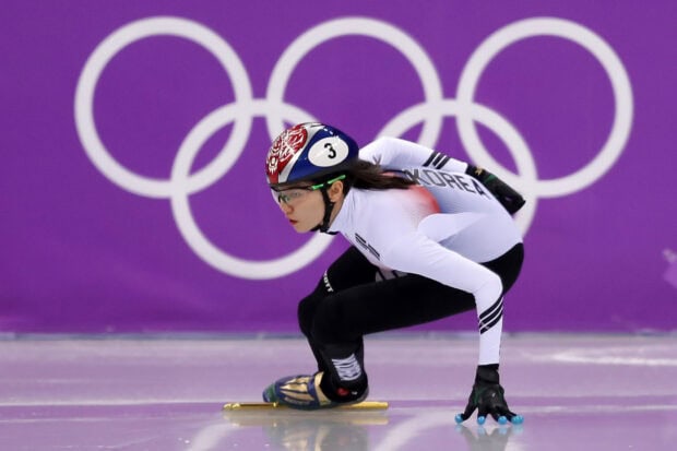 A speed skater from Korea in a crouched position on ice during a professional competition