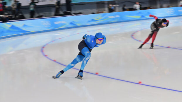 Male speed skater in blue suit competing on ice rink
