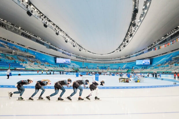 A team of speed skating athletes starting a race on the ice rink at the Beijing 2022 venue