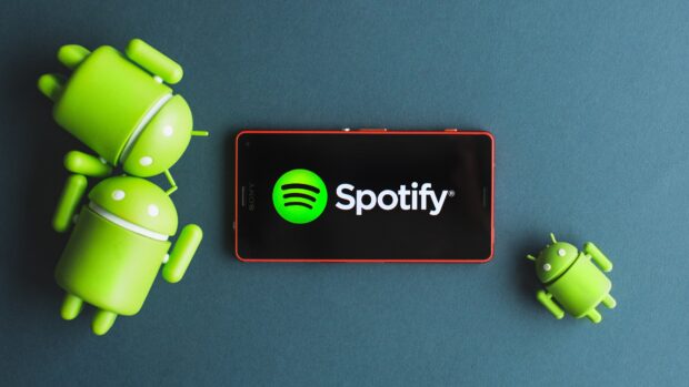 Green Android figures next to a phone displaying Spotify logo on screen