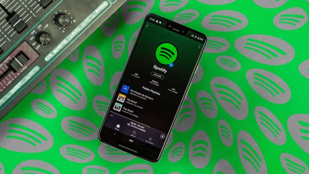 A phone displaying Spotify application on a green surface with multiple Spotify logos