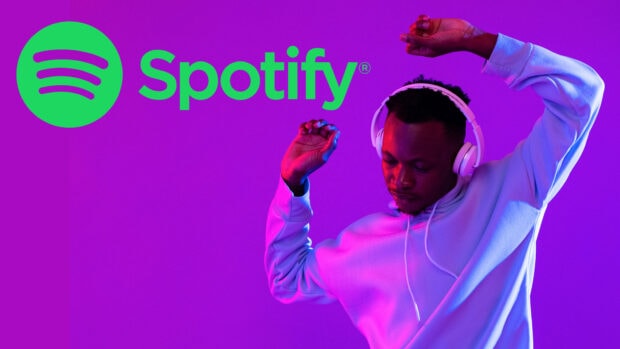 A man enjoying music wearing headphones with Spotify logo in a vibrant purple setting