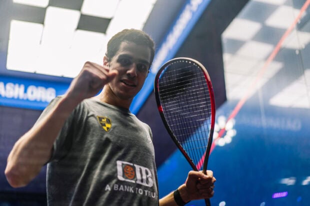 Young squash player celebrating victory in indoor court with racket in hand