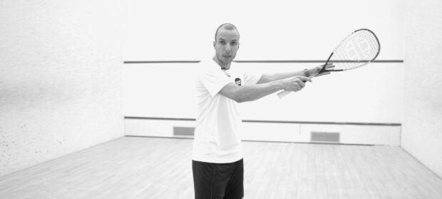 Male squash player demonstrating technique on squash court