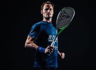 Athletic squash player holding a racket in a ready stance against a dark background