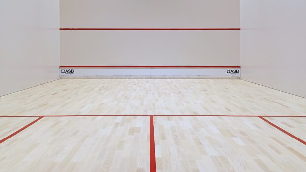 A high quality squash court with wooden floor and red lines ready for play