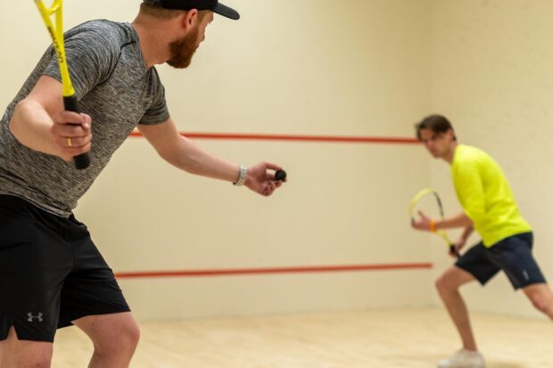 Two players playing squash sport on indoor court in active motion