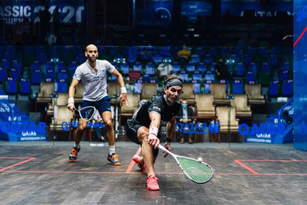 Two squash players competing intensely during a squash sport tournament on a professional court