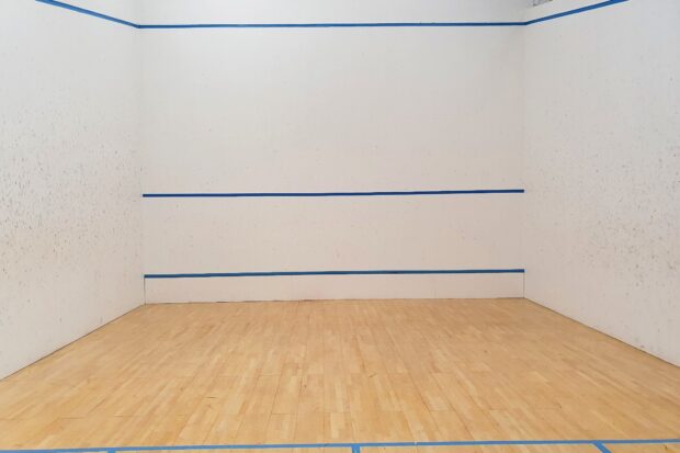 Empty squash court with wooden floor and blue markings