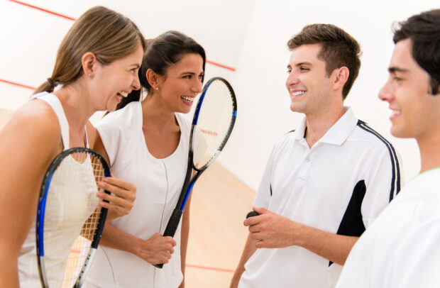 Four players enjoying a friendly squash match on an indoor court