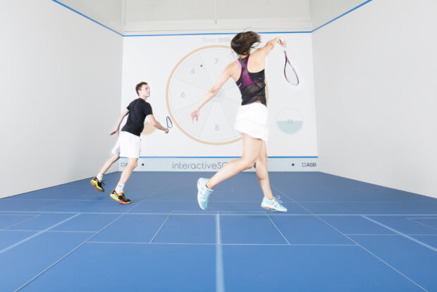 Two players practicing squash sport on indoor court