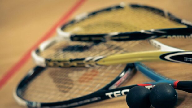 Close up view of squash rackets and balls on a wooden court floor