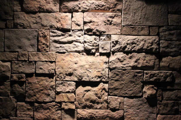 Rough stone texture with various shapes and sizes on a stone wall surface illuminated by soft light