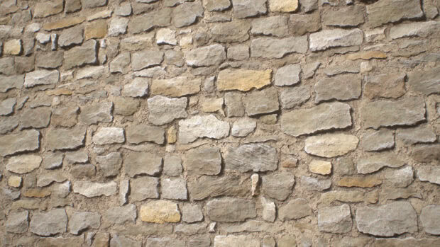 A close up view of natural stone texture with various shapes and colors forming a rustic wall
