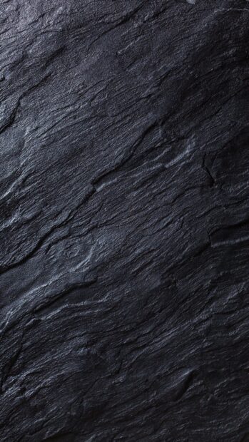 Close up of dark stone texture showing natural rough surface patterns