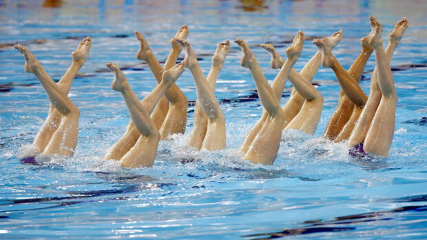 A synchronized swimming team performing a precise leg formation in the water