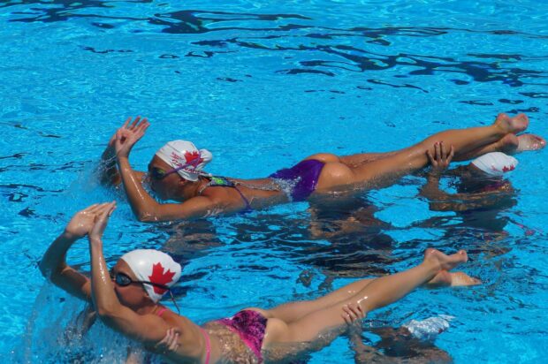 Synchronized swimming athletes performing a routine in a clear blue pool