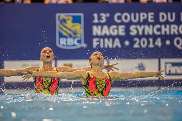 Two synchronized swimmers performing a routine in colorful costumes