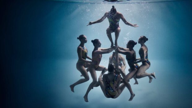 A synchronized swimming team performing an underwater routine in a pool