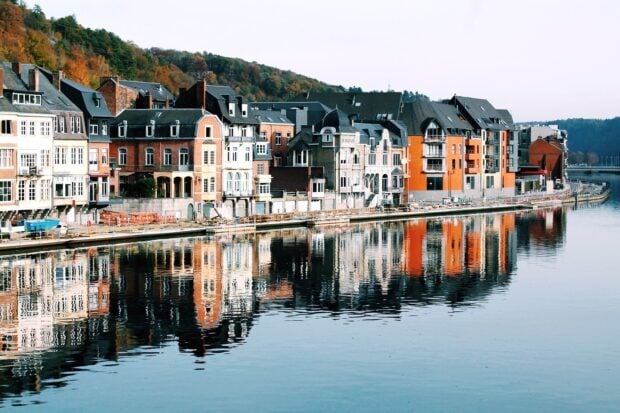 Colorful town buildings reflecting on calm river water in autumn season