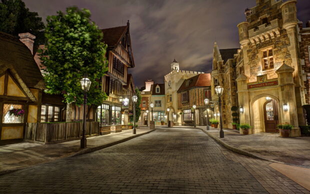 A charming town street with historic buildings and lampposts illuminated at night