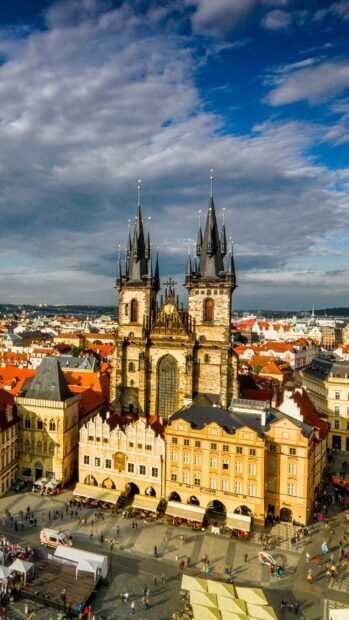 Historic town square with Gothic church and colorful buildings under cloudy sky
