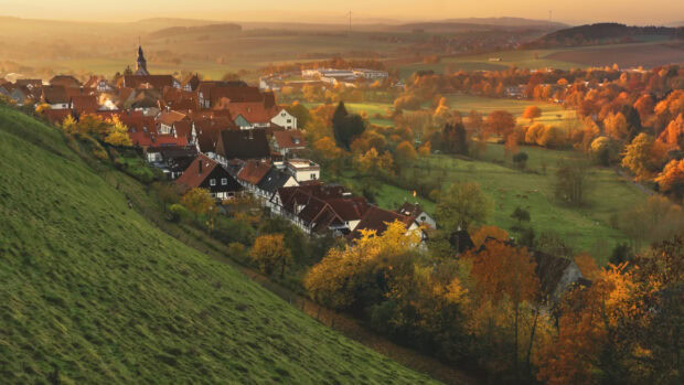 Autumn town scenery with houses and colorful trees on a hillside in a rural area
