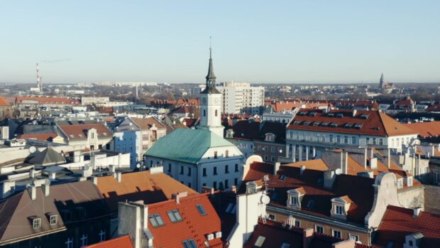 A historic town center with a clock tower and red roof buildings under a clear sky