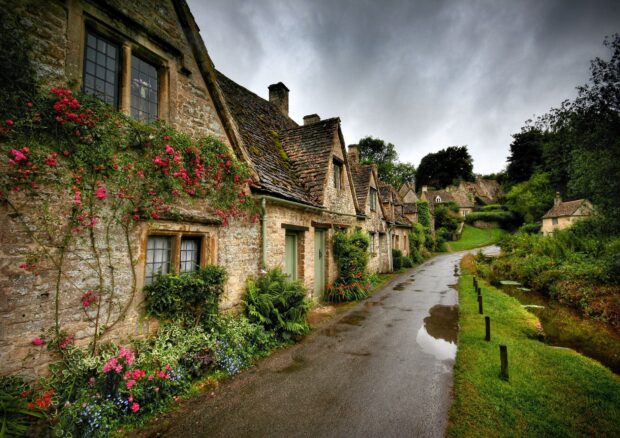 Charming stone town street with blooming flowers and old houses under cloudy sky