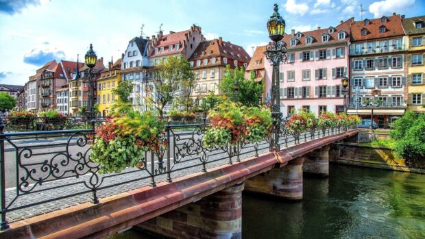 Colorful town view with classic buildings and a flower decorated bridge over the river