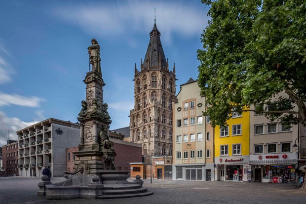 Historic town square with monument and colorful buildings under blue sky