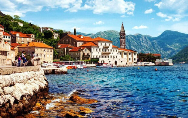 A charming town with red roofs by the blue sea and rocky shore under a bright sky