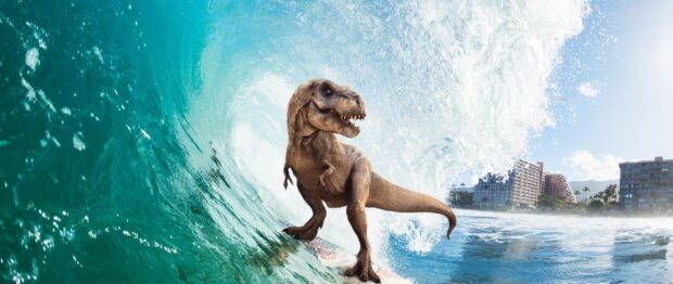 Tyrannosaurus rex riding a surfboard on a large ocean wave near the coast