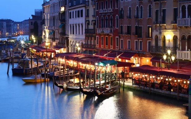 Historic Venice buildings and gondolas lit up along the canal at dusk