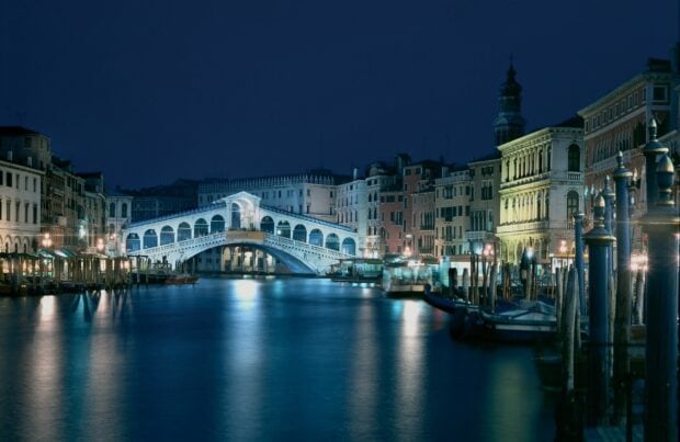 Venice cityscape with illuminated bridge and canals at night in Venice