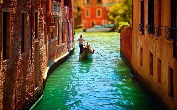 A gondolier navigating a narrow canal between historic buildings in Venice