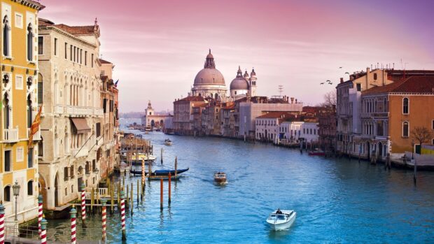 Beautiful Venice canal with historic buildings and boats on a clear blue waterway