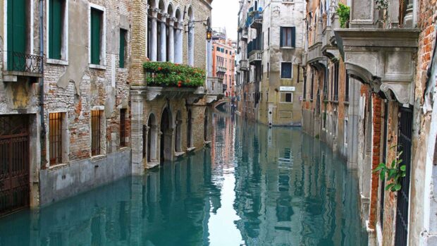 Beautiful ancient Venice canal with old buildings and clear blue water viewed from a bridge