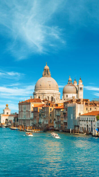 Historic Venice architecture with domes and boats on the water under a blue sky