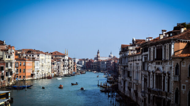 A scenic Venice canal with historic buildings and boats on a clear sunny day