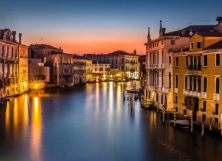 Venice city canal and historic buildings at sunset with calm water reflections