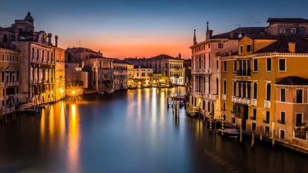 Venice city canal and historic buildings at sunset with calm water reflections