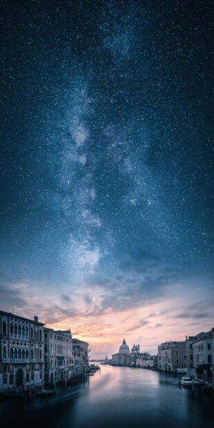 A stunning night sky over Venice with historic buildings lining the canal under a starry sky