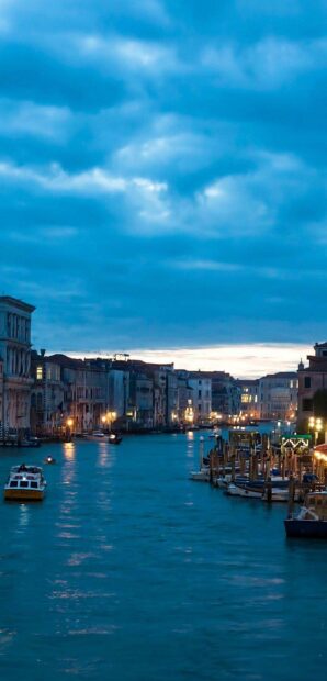 Evening scene of Venice canal with buildings and boats under cloudy sky