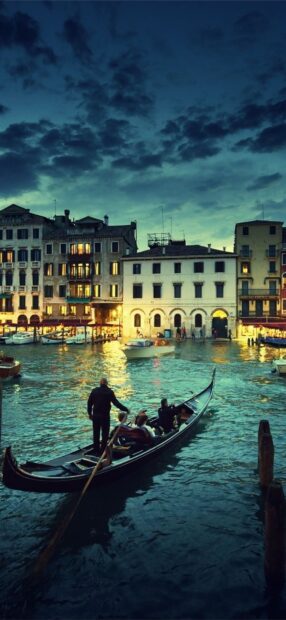 Gondola ride through Venice canals at dusk with historic buildings illuminated along the water