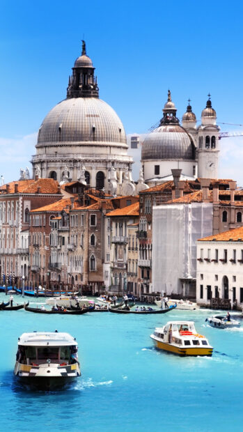 Venice cityscape with historic domes and boats on the turquoise canal water