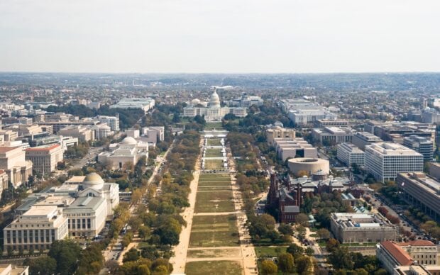 Aerial view of Washington Dc featuring the Capitol building and surrounding monuments and greenery