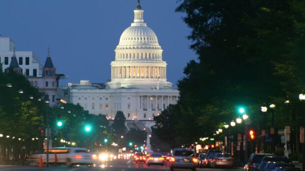 The washington dc building lit up at dusk with busy traffic and green traffic lights